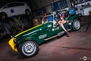 Fille au volant d'une caterham verte et jaune dans un garage